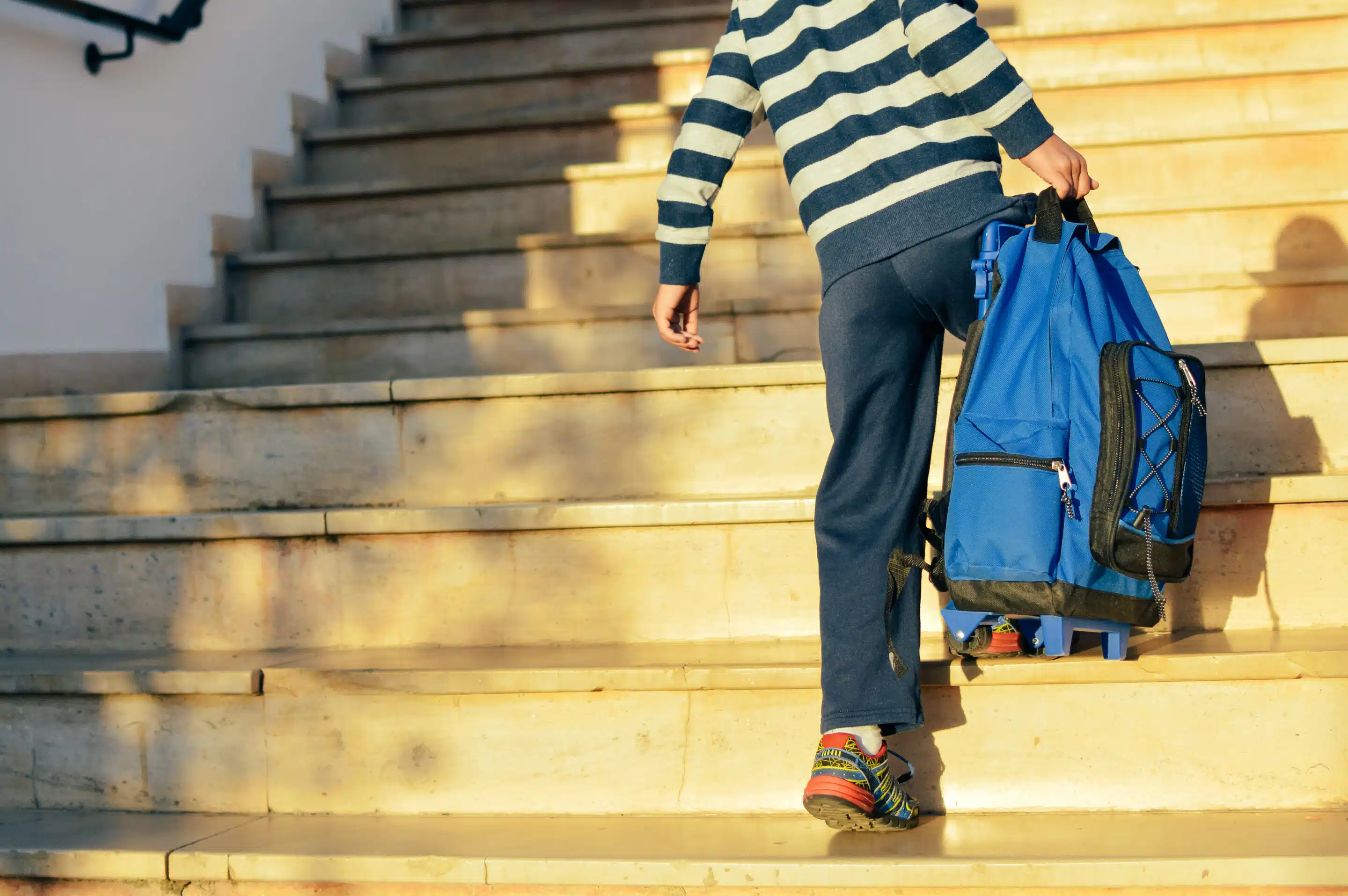 Back,View,Of,Boy,Walking,On,Stairs,Outdoors,Building,Background back-to-school back pain can affect childrens’ academic performance