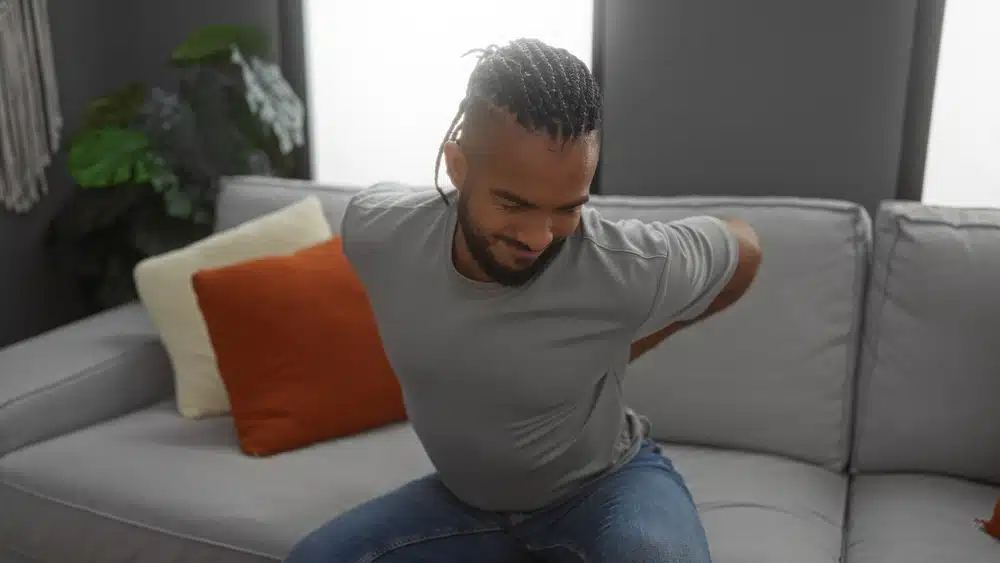 man experiencing SI joint low back pain Man experiencing low back pain shifting weight on hips