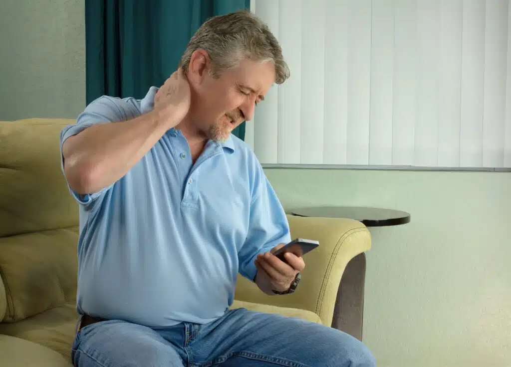 man experiencing neck pain while on phone